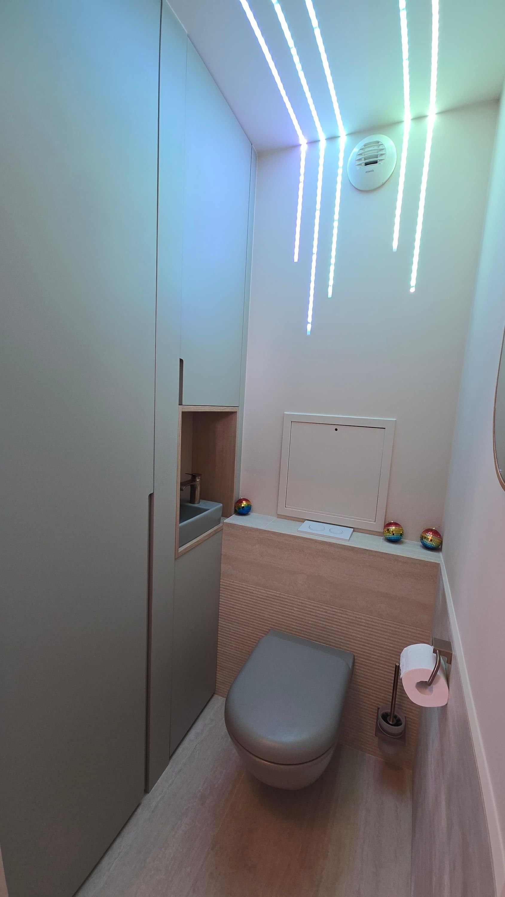 Toilettes avec colonne de rangement laquée vert sauge intégrant un lave-mains et une niche en chêne