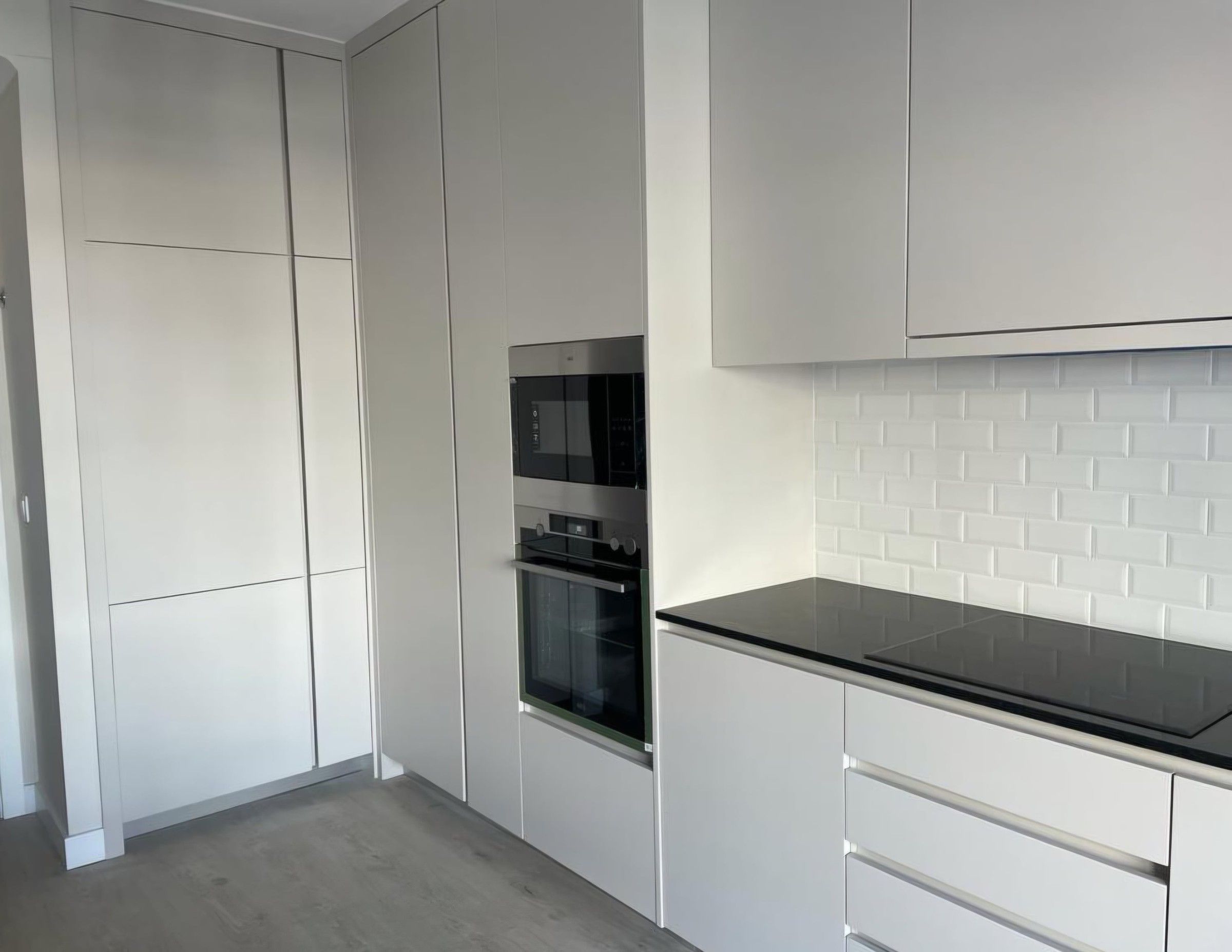 Cuisine claire sans poignées : mur de colonnes, four et micro-ondes encastrés, plan de travail noir