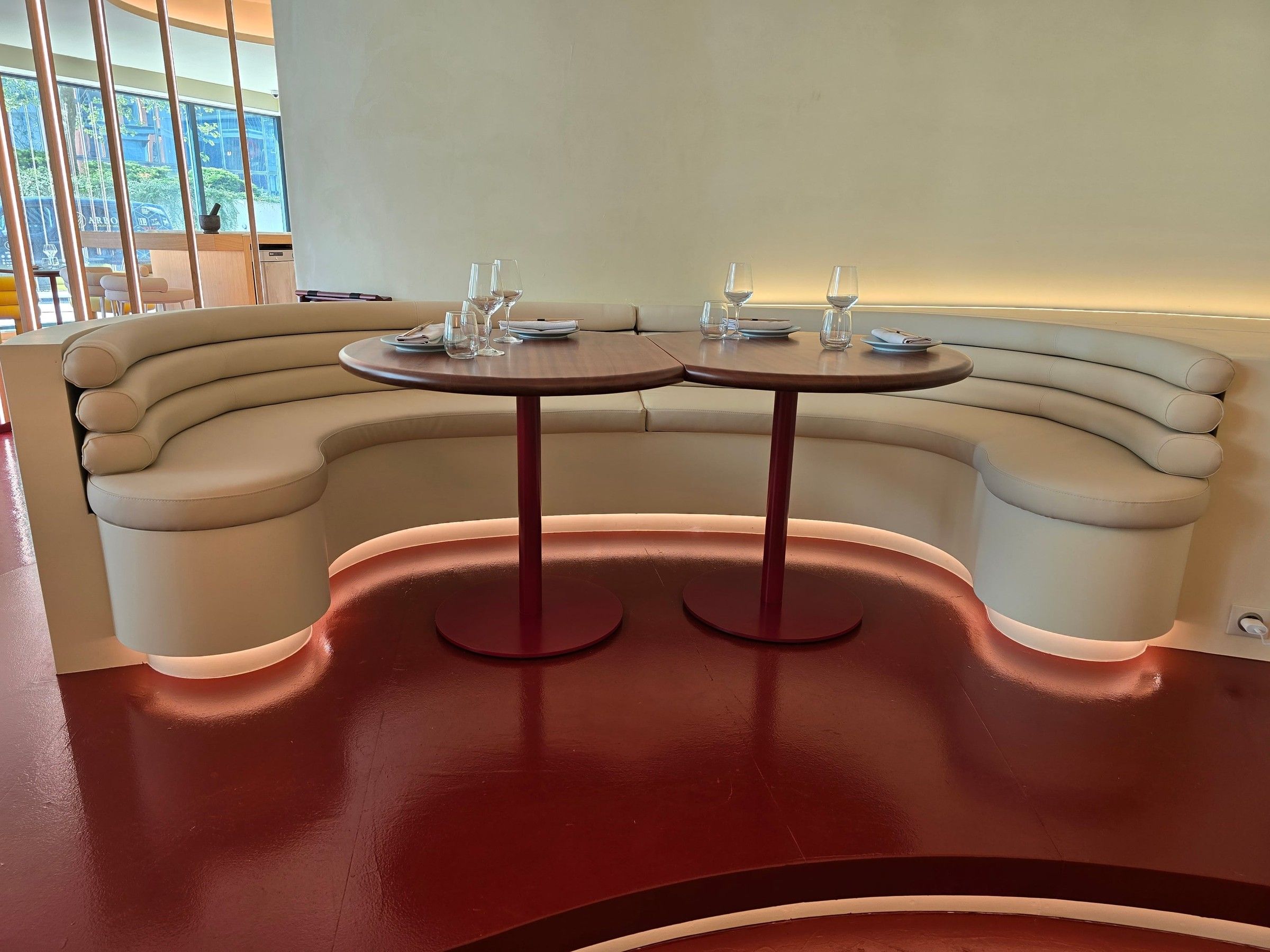 Banquette cintrée crème à deux tables, avec éclairage LED sous l'assise