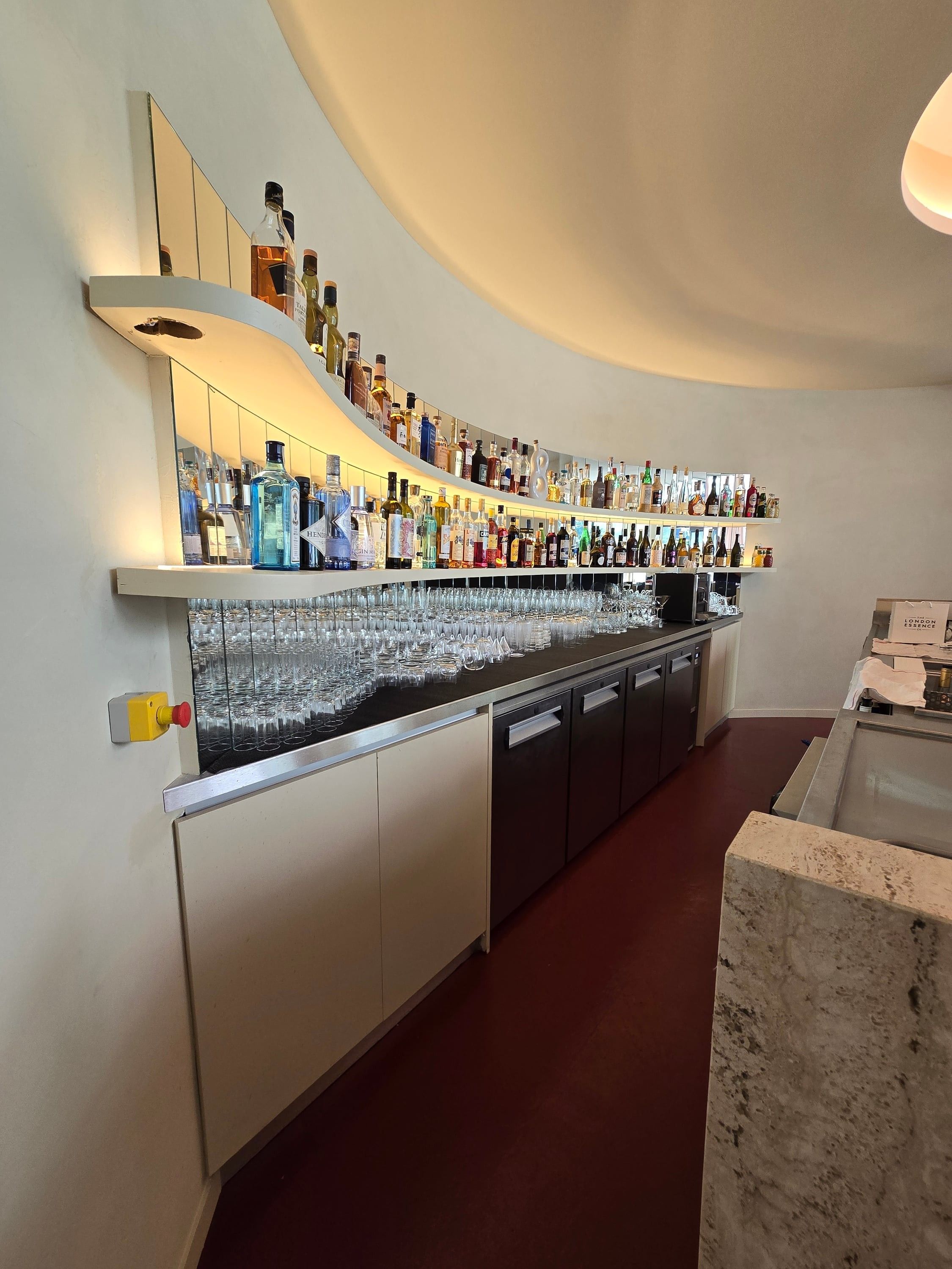 Étagère cintrée rétroéclairée derrière le bar, au-dessus des meubles de service